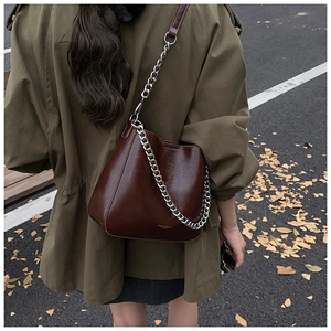 Close-up of deep brown glossy leather bucket bag with chunky silver chain strap detail