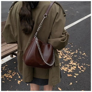 Outdoor shot of a vintage burgundy leather bucket bag with silver chain strap on model