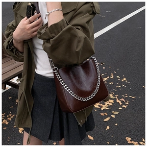 Detail of vintage burgundy oil-wax leather bucket bag with bold silver chain in autumn setting