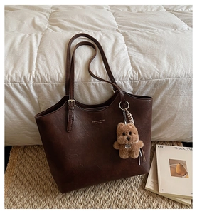 Close-up of vintage dark coffee tote bag with lychee texture and cute bear pendant