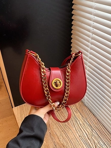 Chic red crescent handbag with golden metal chain and twist lock shown in a stylish setting