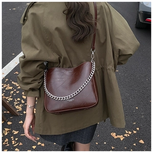 Detailed texture of dark brown leather shoulder bag with chic metal chain and brand logo