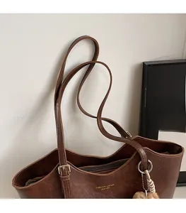 Close-up of adjustable leather shoulder strap and gold hardware on retro brown tote bag