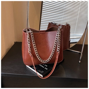 Close-up of retro brown bucket bag with chunky silver chain on mirrored surface
