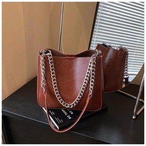 Detail of dark brown leather tote bag with thick silver chain and leather strap