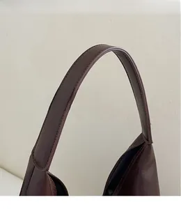 Close-up of seamless long shoulder strap and smooth leather texture on dark brown tote bag