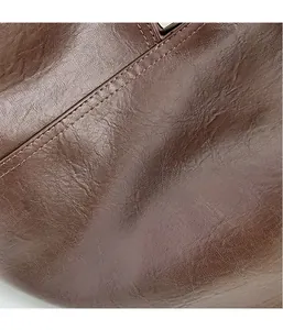 Macro shot of brown leather texture and stitching detail on a large vintage tote bag