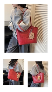 Detail of a large red leather tote bag with a brown plush bear charm and thin shoulder strap