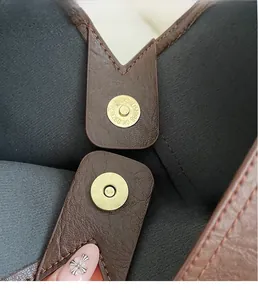 Macro detail of gold magnetic snap closures on a brown textured leather tote bag interior
