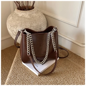 Detail of coffee brown trapezoid bag with thick silver chain and long leather strap