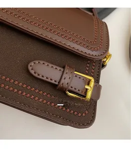Detail of brown vintage flap bag showing suede stitching and gold metallic hardware buckle