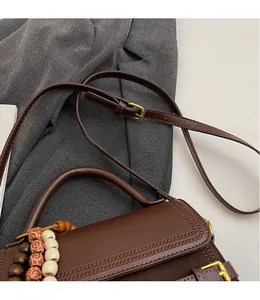 Detail of coffee leather bag featuring hollow-out patterns and adjustable strap
