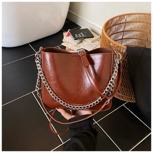 Detail of vintage brown patent leather bucket bag with silver chain and embossed logo