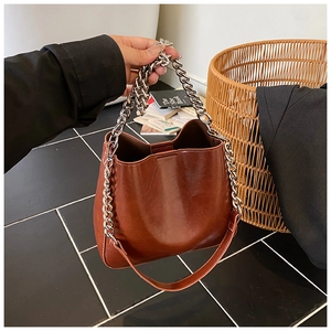 Detail of a brown glossy bucket bag with silver chain handle and wide interior capacity