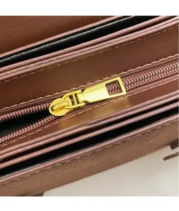 Detail view of smooth golden hardware zipper and inner compartment of brown leather handbag