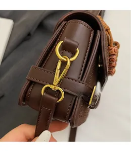 Detail of gold metal hook and wooden bead charm on dark brown vintage leather handbag