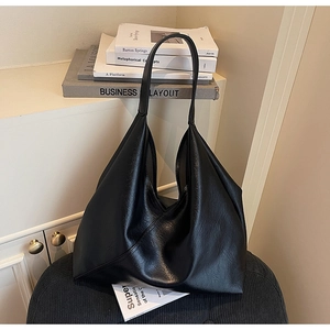 Detailed close-up of textured black leather tote bag with elegant long handles