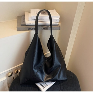 Macro shot of large black leather hobo tote bag featuring a soft texture and wide shoulder strap