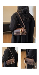 Detail of dark brown vintage handbag with dual buckle accents and colorful beaded charm