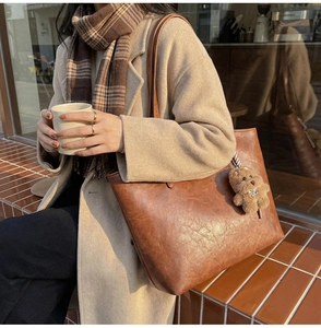 Detail of caramel tote bag with teddy bear charm in an autumn lifestyle setting