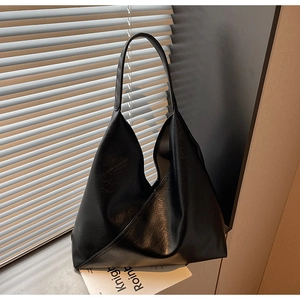 Close-up of black minimalist tote bag with geometric cut design and PU leather texture