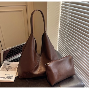 Detail of dark brown leather tote bag with matching zipper pouch on a workspace desk