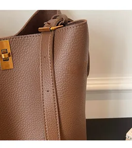 Close-up of premium dark brown lychee pattern leather and gold metal twist lock detail