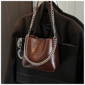 Close-up of brown glossy bucket bag with silver chain and chic urban styling