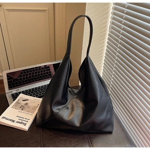Detail of minimalist black leather tote bag on desk with laptop and books for work style