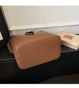 Detailed view of brown bucket bag bottom showing premium lychee grain leather texture