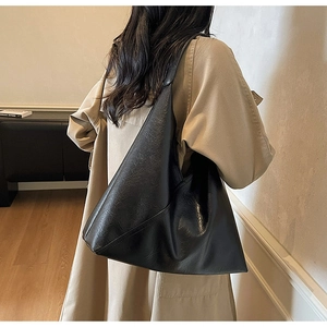 Detail of vintage oil wax leather tote bag with retro pleated texture on beige trench coat