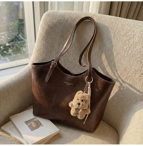 Detailed view of vintage dark brown tote bag with leather texture and plush bear charm