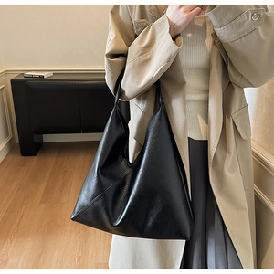 Minimalist black tote bag shown in a professional setting with books and warm lighting