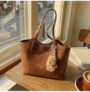 Close-up of vintage brown tote bag texture with a cute plush puppy charm accessory