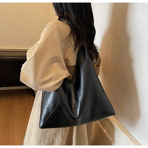 Detailed side view of a large black vintage tote bag with lychee texture and minimalist design