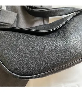 Dettaglio ravvicinato della trama in pelle nera a grana litchi sulla borsa a tracolla