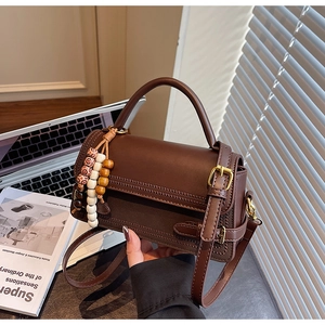 Detail of dark brown retro crossbody bag with vintage beads and gold buckle decoration