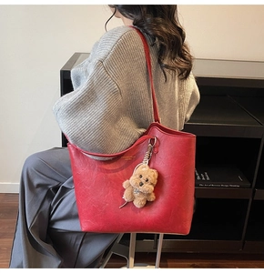 Detail of red wax leather tote bag with gold lettering and plush bear charm