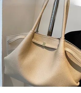 Close-up of beige lychee grain leather tote with elegant golden square buckle detail