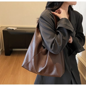 Detail of dark brown leather tote bag with vintage texture and wide shoulder strap