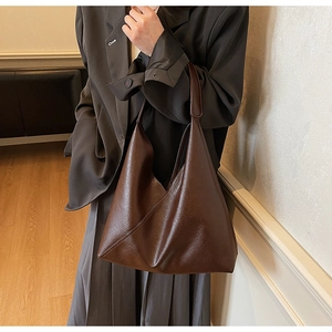 Detail view of large vintage brown tote bag showing supple leather texture and side profile