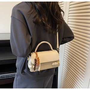 Detail of cream vintage crossbody bag with matte finish and decorative wooden beads