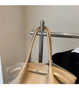 Detail of beige lychee pattern leather tote bag with golden metal buckle on display