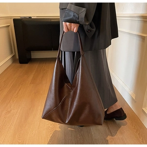 Detail of a large dark brown vintage leather hobo bag with natural grain texture