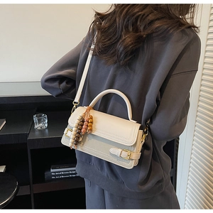 Close-up of a cream retro handbag with contrast stitching and decorative bead tassel