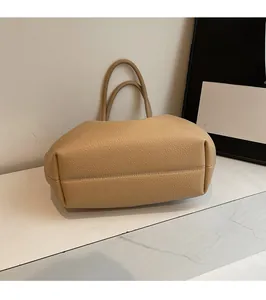 Detailed macro of pebble leather texture and durable bottom stitching on camel tote bag