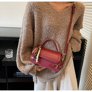 Detail of red matte leather handbag with vintage beads and adjustable strap