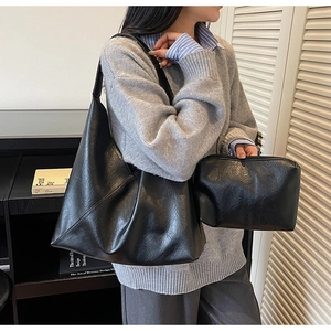 Detail of black vintage leather tote bag set with matching small zipper pouch on model