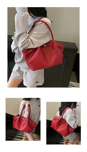Detail of red lychee grain leather tote showing its foldable structure and metal buckle