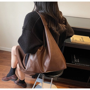 Detailed view of dark brown faux leather texture and wide strap on large tote bag